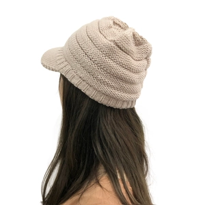 Detail of warm beige chunky knit winter hat with peak visor on female model
