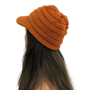 Detail view of the orange knit texture and ear protection on the winter peak hat