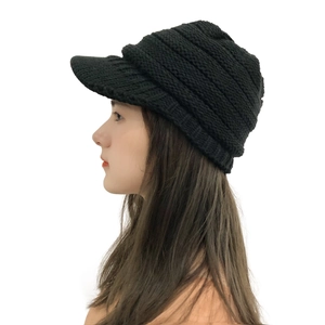 Side view of a black knitted winter hat with a peak brim and ear protection design