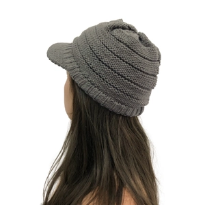 Detail showing dark grey knitted visor beanie with ribbed texture and ear protection