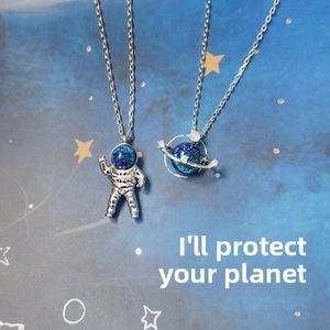 Detail shot of silver astronaut and Saturn pendants with blue sparkling stones on a star theme