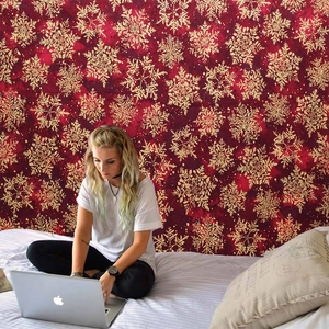 Detail of red Christmas wall tapestry with gold snowflake patterns in a cozy bedroom decor