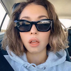 Woman wearing stylish black cat eye sunglasses in a car setting with sun protection