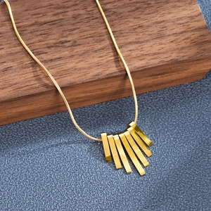 Detailed shot of gold bar pendant necklace on wood with polished metal vertical bars