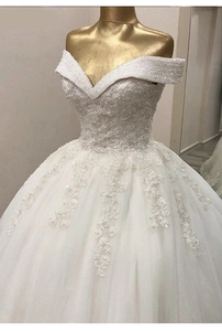 Détail d'une robe de mariée à épaules dénudées avec broderies de dentelle et sequins