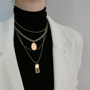 Detail view of multi-layer gold titanium steel necklace with round and rectangle pendants