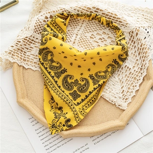 Detailed view of yellow paisley headband with elastic band on decorative tray