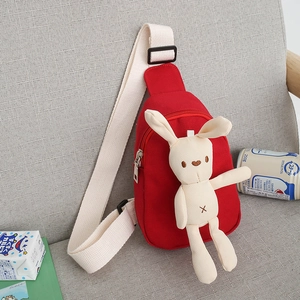 Red kids canvas chest bag featuring a cute white plush bunny on a soft grey sofa