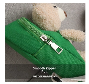 Detail showing smooth silver zipper pull on green canvas bag with plush bear decor