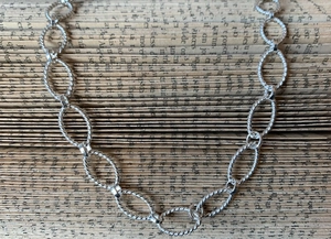 Close-up of twisted oval link necklace laid on vintage book pages background