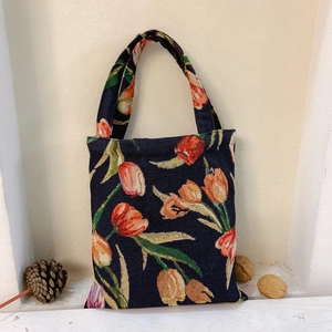 Detailed texture of navy jacquard handbag with vintage orange tulip floral patterns