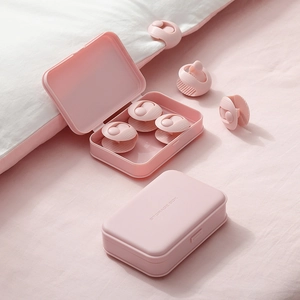 Pink sheet grippers and storage boxes used on white bedding for secure mattress fit