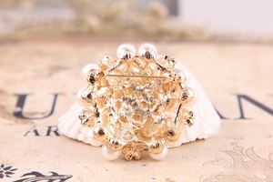 Macro shot of gold-plated hollow floral brooch back with secure safety pin and pearls