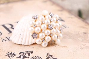 Macro shot of elegant floral pearl brooch with rhinestones on a decorative seashell