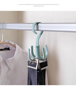 Close-up of a rotating light green four-claw hanger holding a black belt in a closet