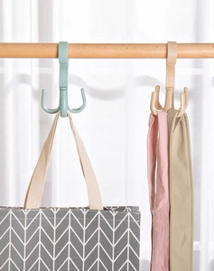 Rotating four-claw hook in green and khaki holding bags and scarves on a wooden rod