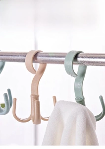 Close-up of a rotating 4-claw hook in light brown and green for hanging ties and bags