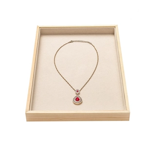 Vintage gold necklace with red teardrop gemstone in a wooden jewelry display tray