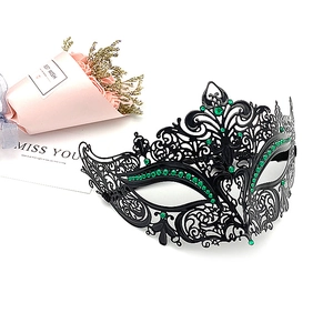 Detail of a black metal masquerade mask with green rhinestones and laser-cut patterns