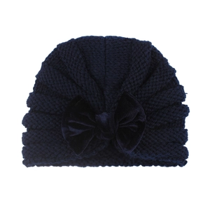 Detailed view of dark navy knit baby beanie with large velvet bow decoration