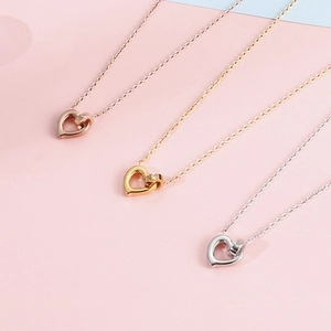 Hollow heart pendant necklaces in rose gold, gold and silver on pink background