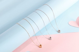 Close-up of hollow heart pendants in gold, silver, and rose gold on a necklace