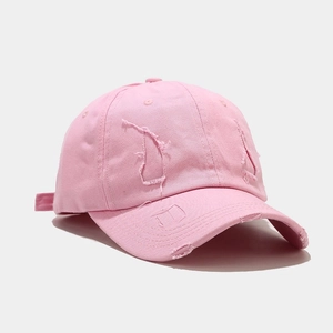 Detailed close-up of distressed brim and worn fabric on pink vintage baseball cap