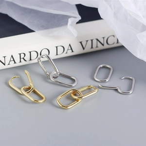 Detail of oval S925 sterling silver hoop earrings in polished gold and silver finishes