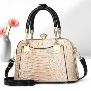 Elegant beige crocodile-pattern handbag with black handles and crystal clasp detail