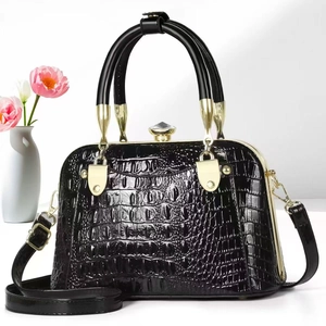 Detail of black crocodile embossed patent leather handbag with luxury gold hardware