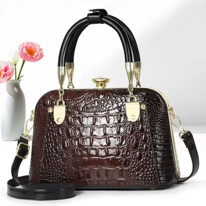 Detail of crocodile embossed leather handbag with gold frame and gem-shaped knob lock