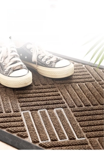 Detail of dark brown door mat with raised striped texture for effective dust removal