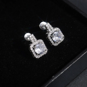 Close-up of square zircon stud earrings with micro-paved halo on black velvet