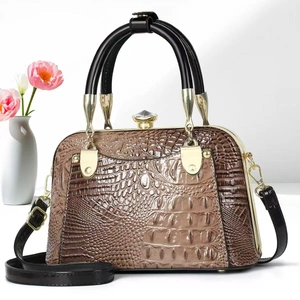 Close-up of brown crocodile pattern handbag with elegant diamond clasp and gold accents