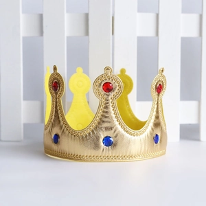 Close-up of golden fabric crown with red and blue gemstones on white grid background