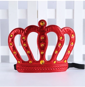 Coiffe couronne en tissu rouge avec des détails strass dorés pour fête, gros plan.