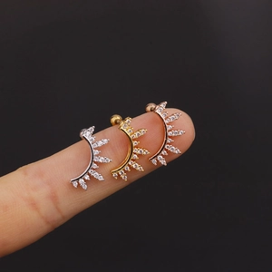 Macro view of silver, gold and rose gold zircon curved earrings set on a finger