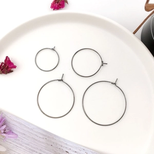 Set of four gunmetal gray round earring hoops in two sizes displayed on a white plate
