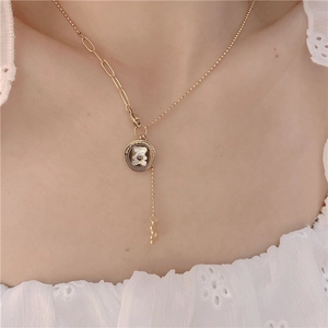 Detail of gold asymmetric necklace with white bear mother of pearl pendant on model