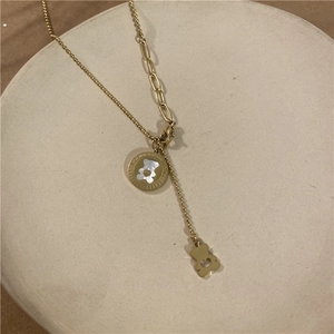 Detailed shot of golden bear necklace with white shell inlay on ceramic tray