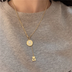 Detail of bear pendant necklace with mother of pearl on a textured grey sweater