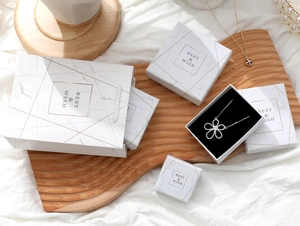 Detailed set of marble pattern jewelry boxes and gift bags on a wooden tray