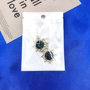 Boucles d'oreilles tournesol en strass dans un sachet plastique sur fond bleu