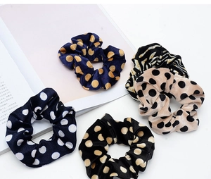 Close-up of five elastic velvet scrunchies with polka dot and zebra print patterns