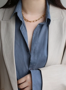 Close-up of polished gold paperclip chain necklace worn with an elegant blazer