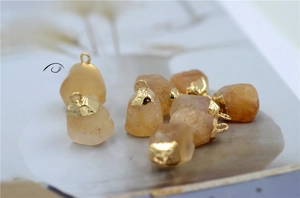 Macro view of raw citrine gemstone pendants with gold plated edges for DIY jewelry