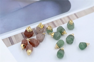 Macro detail of natural faceted rose quartz and aventurine stone pendants with gold caps