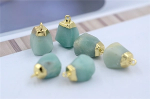 Close-up of raw natural stones with gold-plated edges and hanging loops in detail