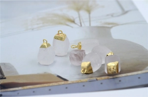 Detailed view of six raw rose quartz pendants with gold plated caps on a magazine