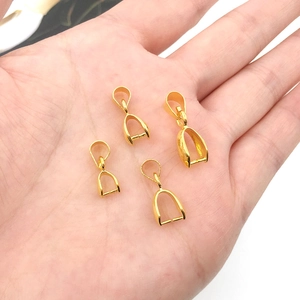 Macro shot of four gold copper pendant clasps in different sizes held on a palm for scale